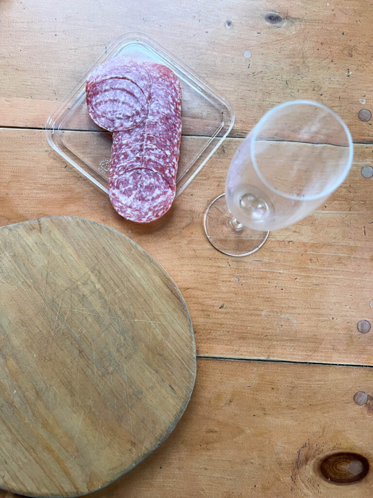 Assemble your supplies to create a rose salami - board, champagne flute and salami
